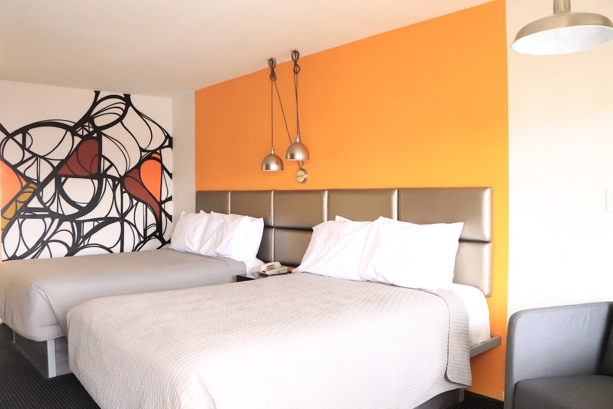 2 Double Beds — orange accent wall with two beds and pendant lights